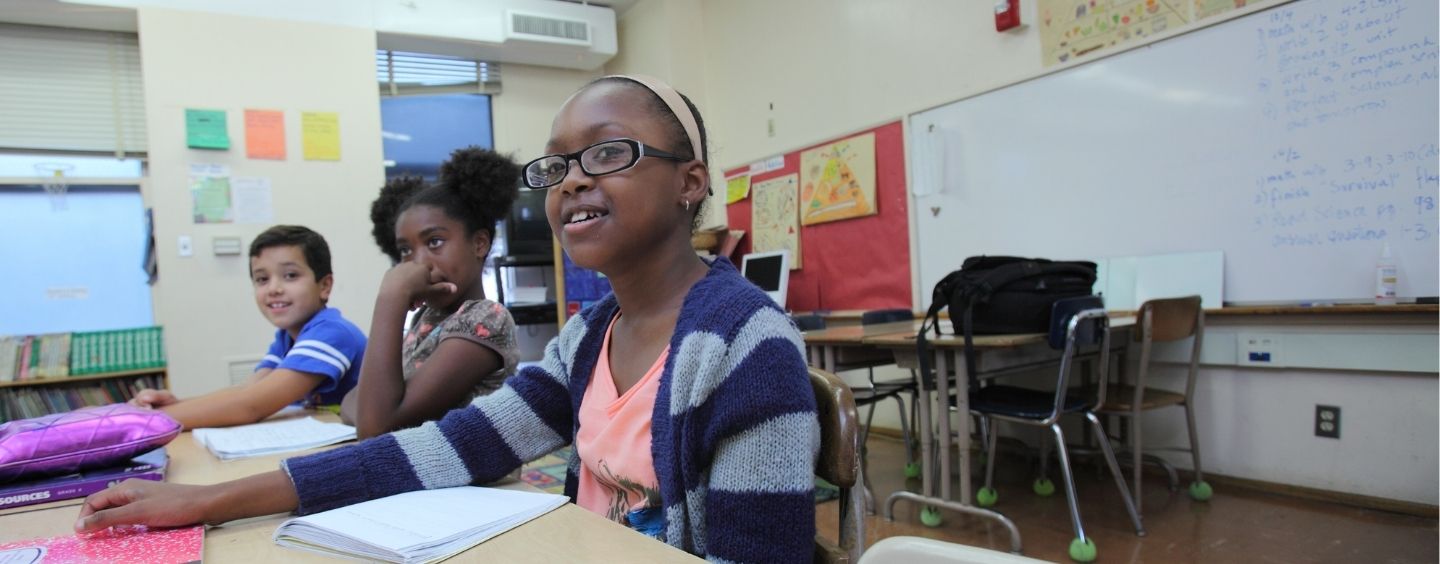 three elementary students of color in a classroom